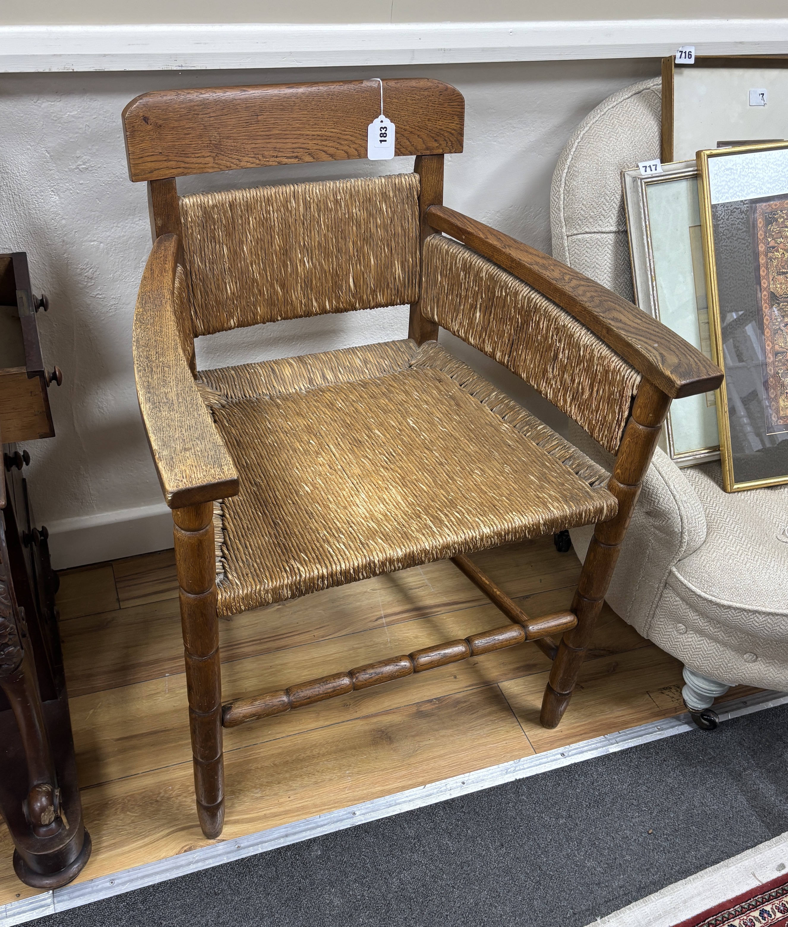 An Arts and Crafts style oak elbow chair with rush seat and back, width 60cm, depth 44cm, height 83cm